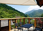夏の日差しで輝く緑に囲まれた里山ヒュッテ。里山ヒュッテ宿泊特典の貸切温泉露天風呂1回60分間無料付。